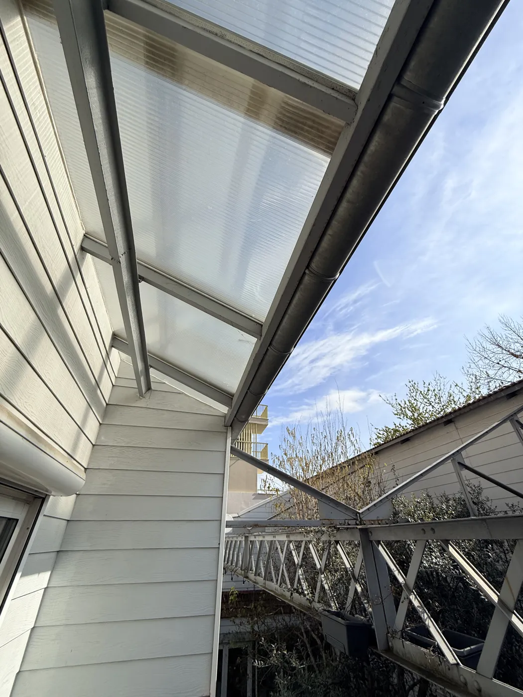 Avant : ancienne verrière en polycarbonate jauni sur une structure inadaptée, vue de l'extérieur